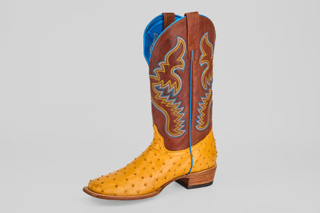 The Ransom - Buttercup - Square Toe Boot from the Platinum Collection features a yellow Exotic Full Quilt Ostrich leather foot, brown shaft with yellow and blue stitching, blue lining, and wooden heel against a plain light gray background.