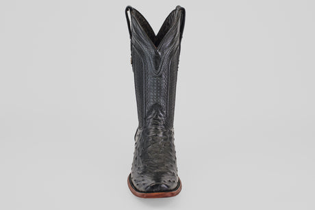 The Exotic Ostrich - Black - Narrow Square Toe boot is shown from the front against a white background, showcasing its textured leather, high shaft, brown sole, and signature narrow square toe design.