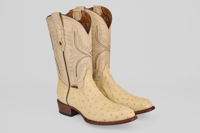 The Exotic Full Quilt Ostrich - Bone - Round Toe boots feature textured genuine ostrich leather in light tan, decorative stitching on the shaft, pull straps at the top, and brown wooden heels.