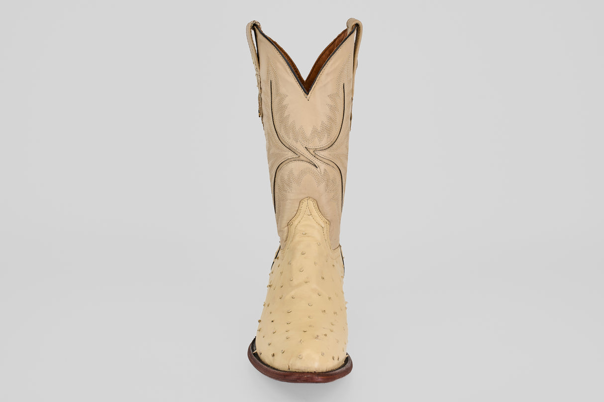 The Exotic Full Quilt Ostrich - Bone features a single genuine ostrich leather cowboy boot in beige with a round toe, decorative shaft stitching, and dark brown sole, displayed facing forward on a plain light background.