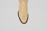 A top-down view of the Exotic Full Quilt Ostrich - Bone - Round Toe cowboy boot’s toe, featuring beige genuine ostrich leather and a brown sole, showcases its luxurious texture and craftsmanship against a white background.