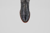 A top-view close-up of the Exotic Full Quilt Ostrich - Black - Round Toe boot, featuring textured black ostrich leather and a brown sole against a white background, highlights its classic Western style.