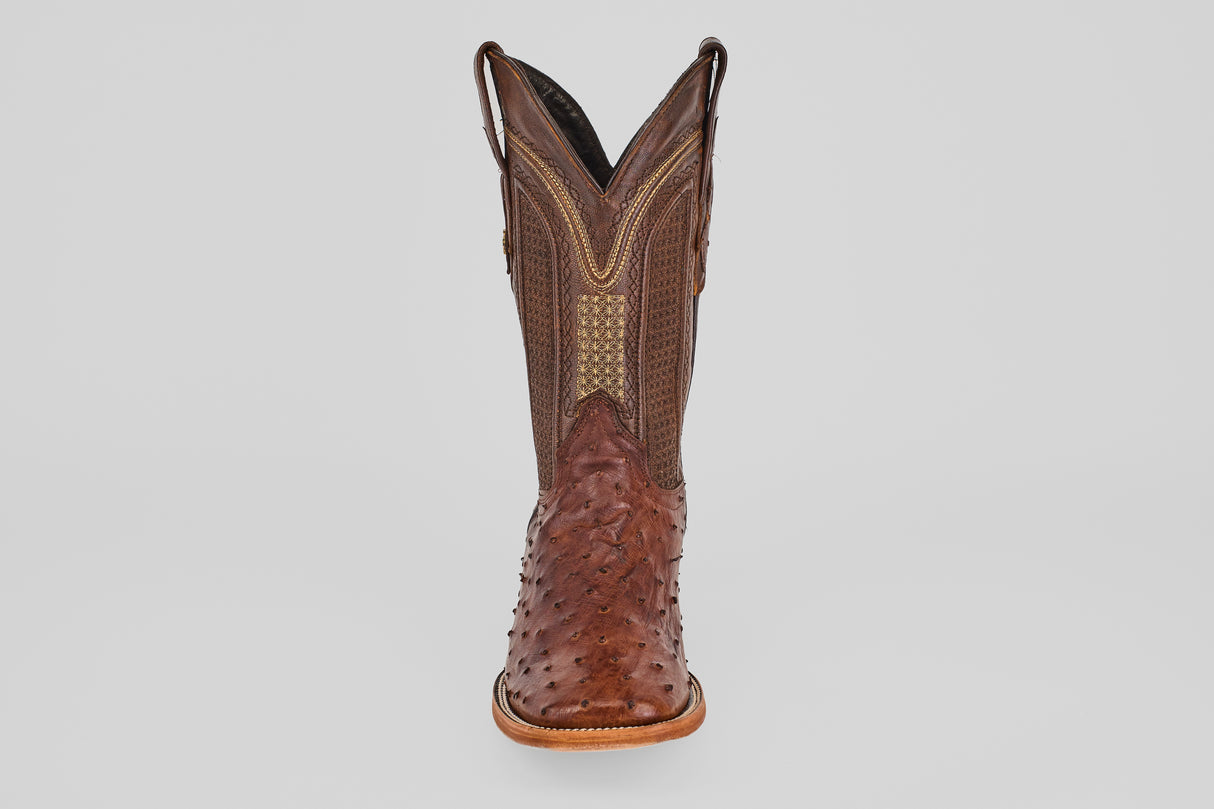 A single Exotic Full Quilt Ostrich - Brown - Square Toe boot made of textured leather with intricate stitching and a patterned toe and shaft, reminiscent of ostrich boots, is shown from the front against a plain light background.