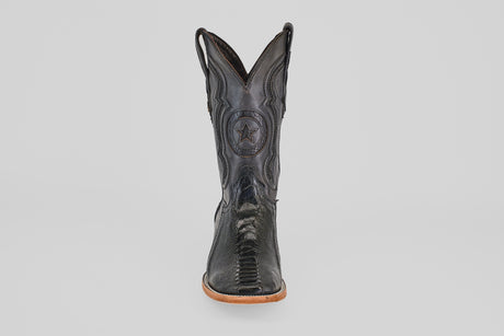 The Austin Leg - Black - Square Toe boot features decorative stitching, a star emblem on the shaft, and a light tan sole. Photographed from the front on a plain light gray background, it's ideal for square toe boot enthusiasts.