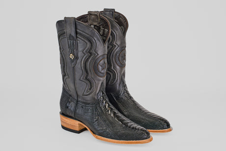 The Austin Leg - Black - Roper Toe boots feature intricate stitching, embossed star designs, decorative pull straps, and a light brown wooden heel and toe, pictured side by side on a light gray background.
