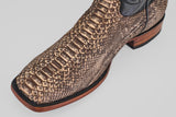 A close-up of the Tanner - Rustic Bone - Square Toe boot highlights its brown python design, black trim, and wooden sole, showcasing Western craftsmanship against a light gray background.