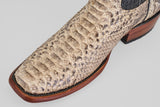 Close-up of the Tanner - Natural boots, crafted in beige python leather with a narrow square toe, showcasing detailed texture, a wooden sole, and black stitching.