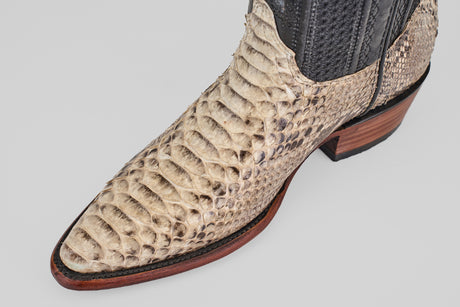 A close-up of the Tanner - Natural - Snip Toe cowboy boot, crafted from light snakeskin with a snip toe, dark stitching, and a stacked leather heel, displayed against a plain gray background.