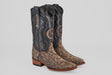 The Tanner – Rustic Bone – Snip Toe boots feature dark brown leather uppers, light brown snakeskin-patterned lowers, stacked wooden heels, and decorative stitching for a western-inspired look.