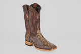The Tanner – Dune – Square Toe boot features a brown leather upper, textured snakeskin-patterned lower section, decorative stitching, and a light wooden heel, displayed against a plain gray background.