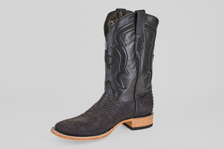 A single Tanner - Matte Black - Square Toe cowboy boot with scaly black python texture and decorative stitched leather shaft. It has a light tan wooden heel and sole, shown against a plain light background. Model: PN30.