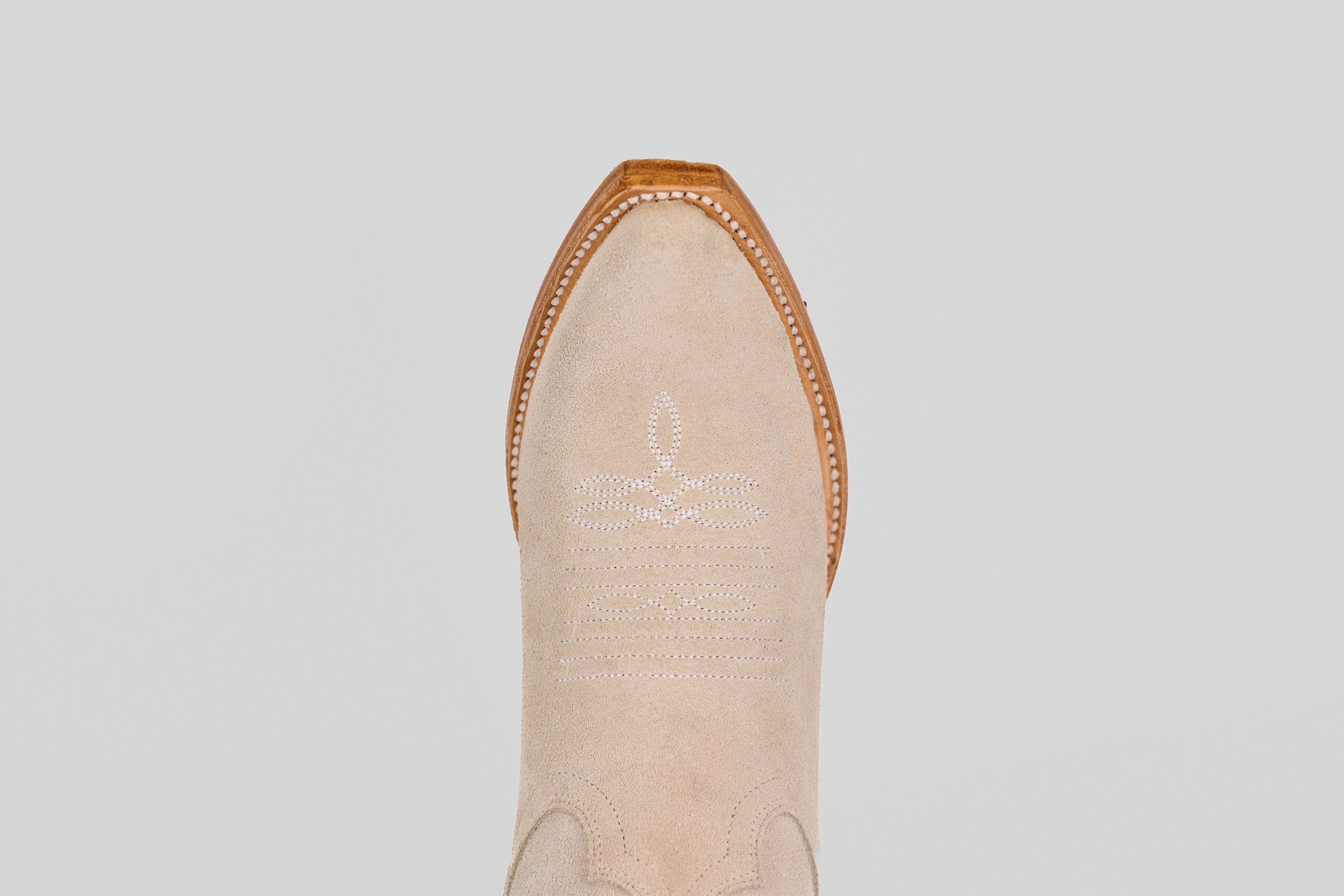 A top-down view of the Allison Ivory - Tall Shaft - Snip Toe boot highlights its ivory color, snip toe, white decorative stitching, and brown leather trim, exemplifying classic women's western boot style.