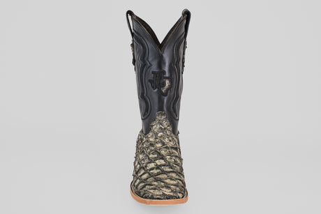 The Conor - Rustic Bone - Square Toe men's cowboy boot features a black leather upper and textured, scaly tan fish leather lower section, shown from the front on a plain light gray background.
