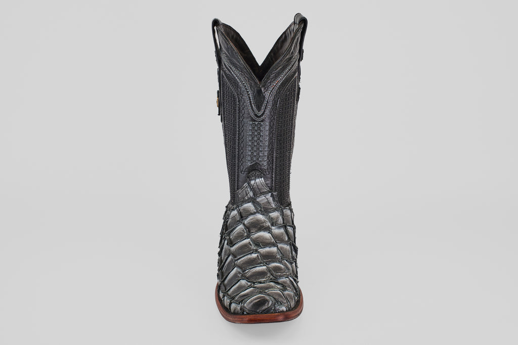 The Conor - Newspaper boot features a black, narrow square toe with a reptile-textured foot, decorative shaft stitching, and a brown sole, shown facing forward against a plain light background.