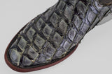 Close-up of the Conor - Charcoal - Roper Toe, a men's cowboy boot featuring textured, glossy reptile skin with distinct raised scales and a brown leather sole—an elegant update to classic Western style.