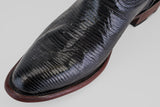 Close-up of the Blaze – Black – Round Toe shoe featuring shiny, textured black leather and a dark brown sole with detailed lines and a slightly worn look, set against a light background.