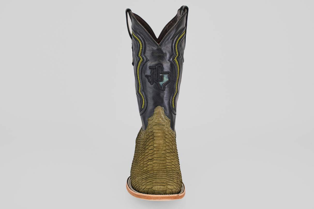 The Tanner - Green Jungle - Square Toe boot features a textured green snakeskin foot, a black leather shaft with yellow and green stitching, and classic western style, shown front-facing on a plain light background.