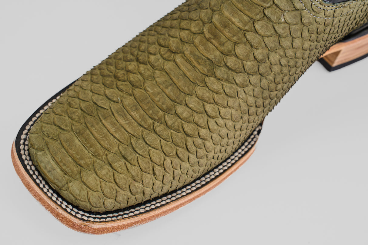 Close-up of the Tanner - Green Jungle - Square Toe cowboy boot, featuring green, python-textured leather and detailed light brown, black, and white stitching—ideal for a standout western look.