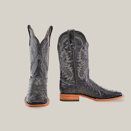 Set against a white backdrop, the Karoo Ostrich Print Black - Square Toe cowboy boots feature intricate stitching and authentic ostrich texture. The left boot stands upright, while the right angles downward, highlighting their handcrafted charm.