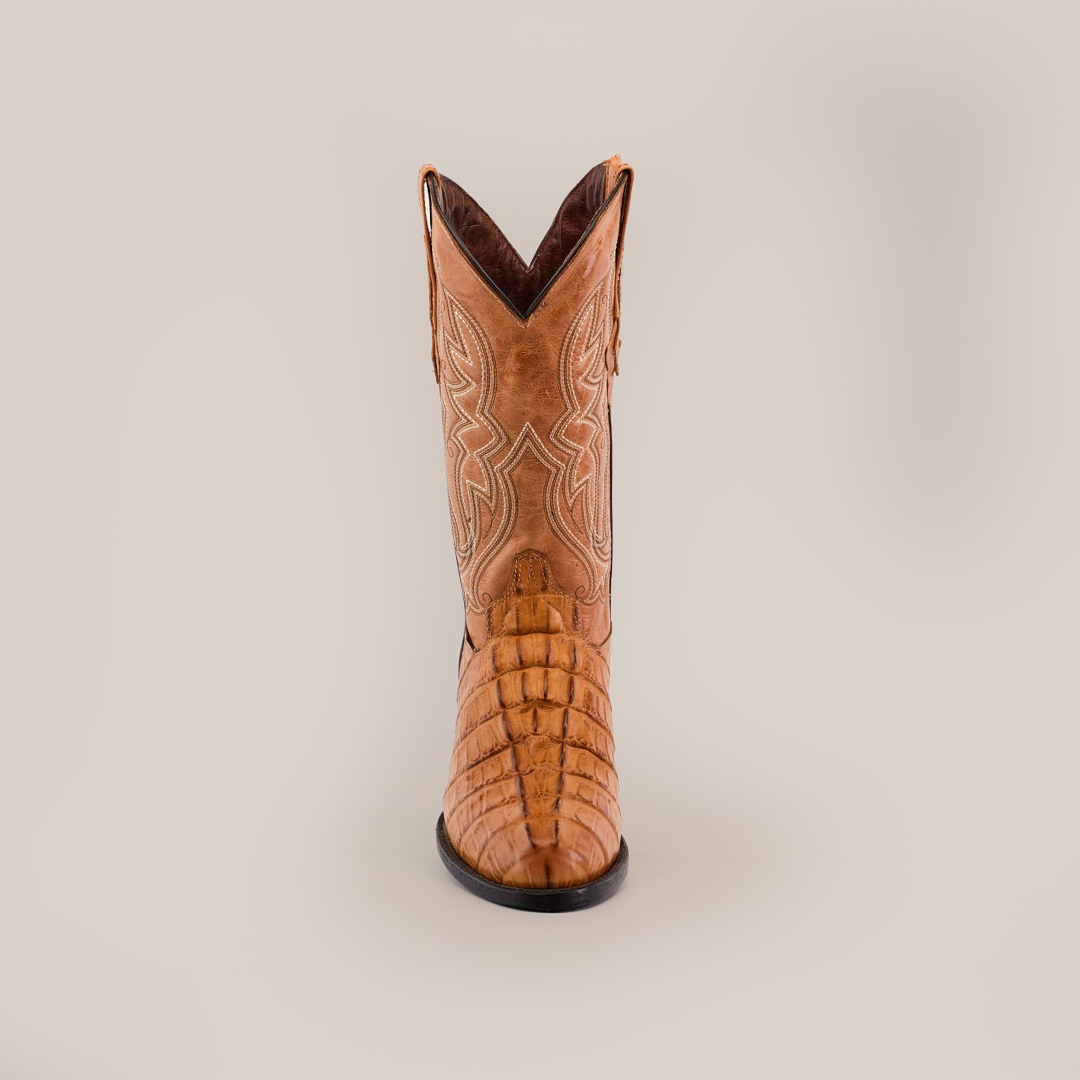 A cowboy boot with detailed stitching and premium textured cowhide leather is centered on a white background. The Crocodile Tail Print Orix - Round Toe boot showcases a pointed toe, raised heel, intricate patterns, and handcrafted craftsmanship.