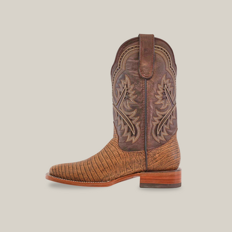 The Lizard Print Tabaco - Square Toe is a brown handmade cowboy boot with detailed stitching, a square toe, wooden heel, and a pull strap. The shaft features elaborate embroidered patterns against a lighter texture.