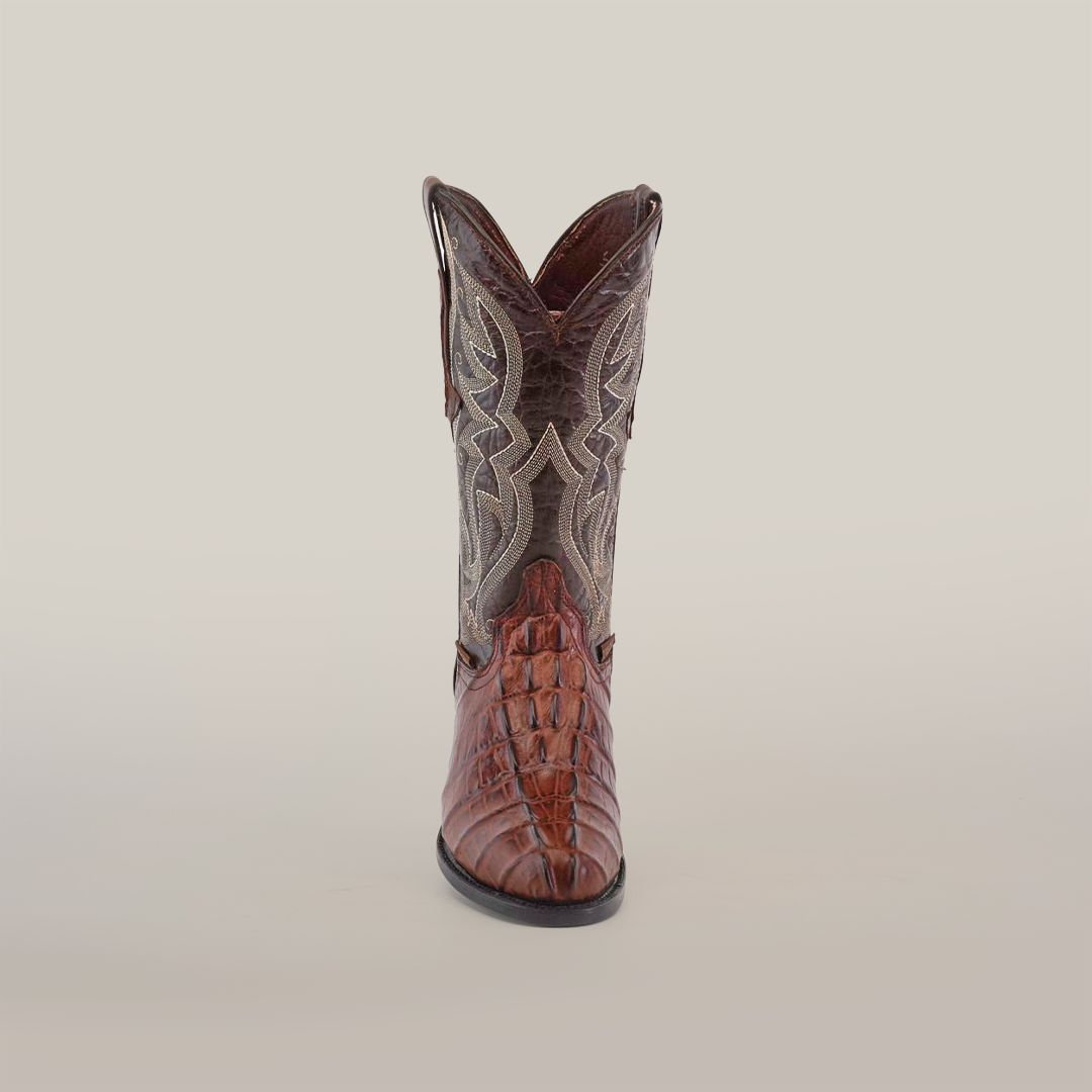 A front view of a single Crocodile Tail Print Chocolate - Round Toe cowboy boot showcases a textured surface and intricate stitching, all set against a plain white background, highlighted by its premium cowhide finish.