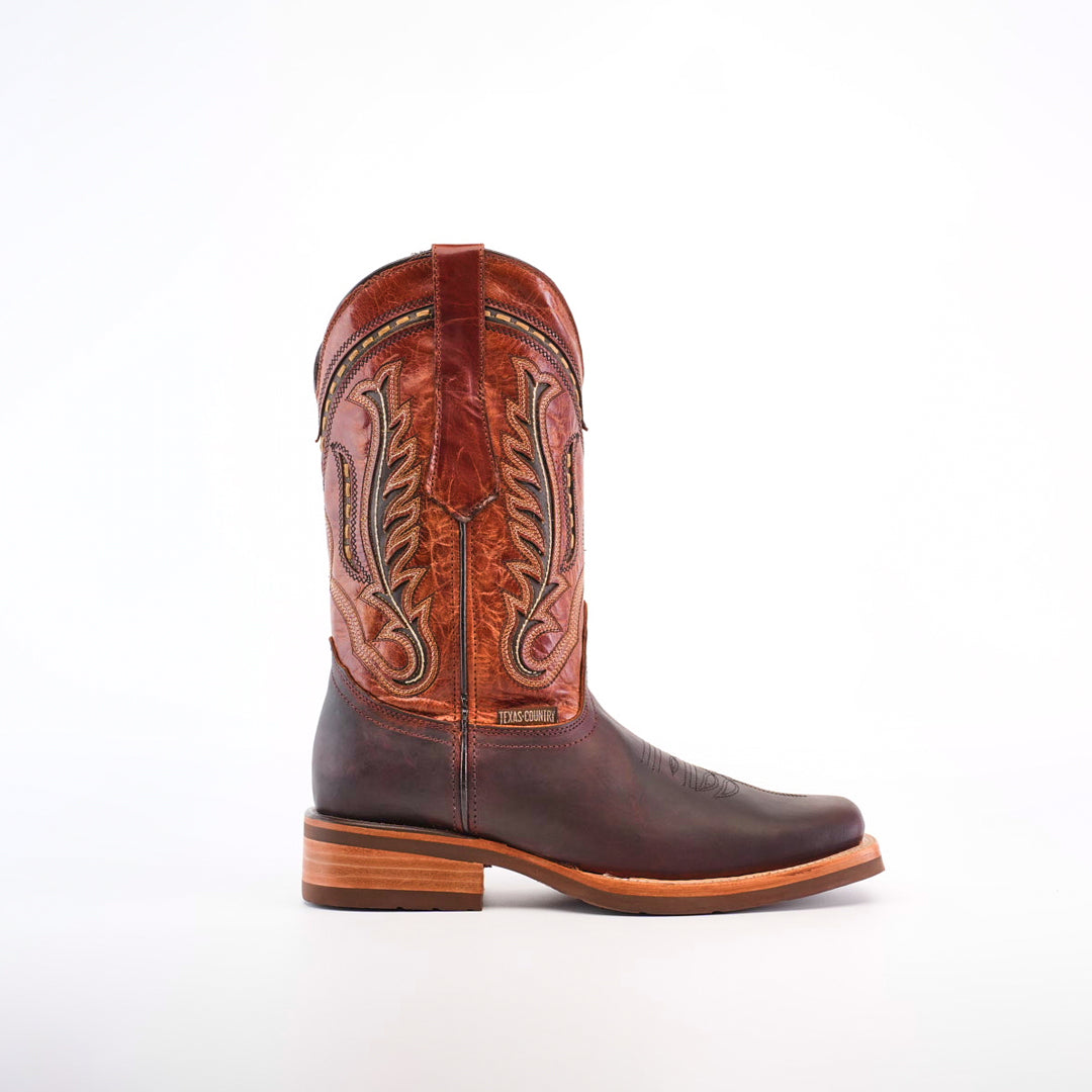 An Azkar Moka Rodeo Toe cowboy boot showcases a brown lower and detailed reddish-brown upper made of premium cowhide. It features a wooden heel and slip-resistant sole, all set against a white background.