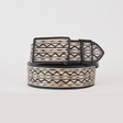 The Artisanal Handmade Silver Belt ZigZag features black zigzag and diamond designs on a beige background. Rolled up with the buckle on top against a white backdrop, its handcrafted beauty is sure to make a statement.