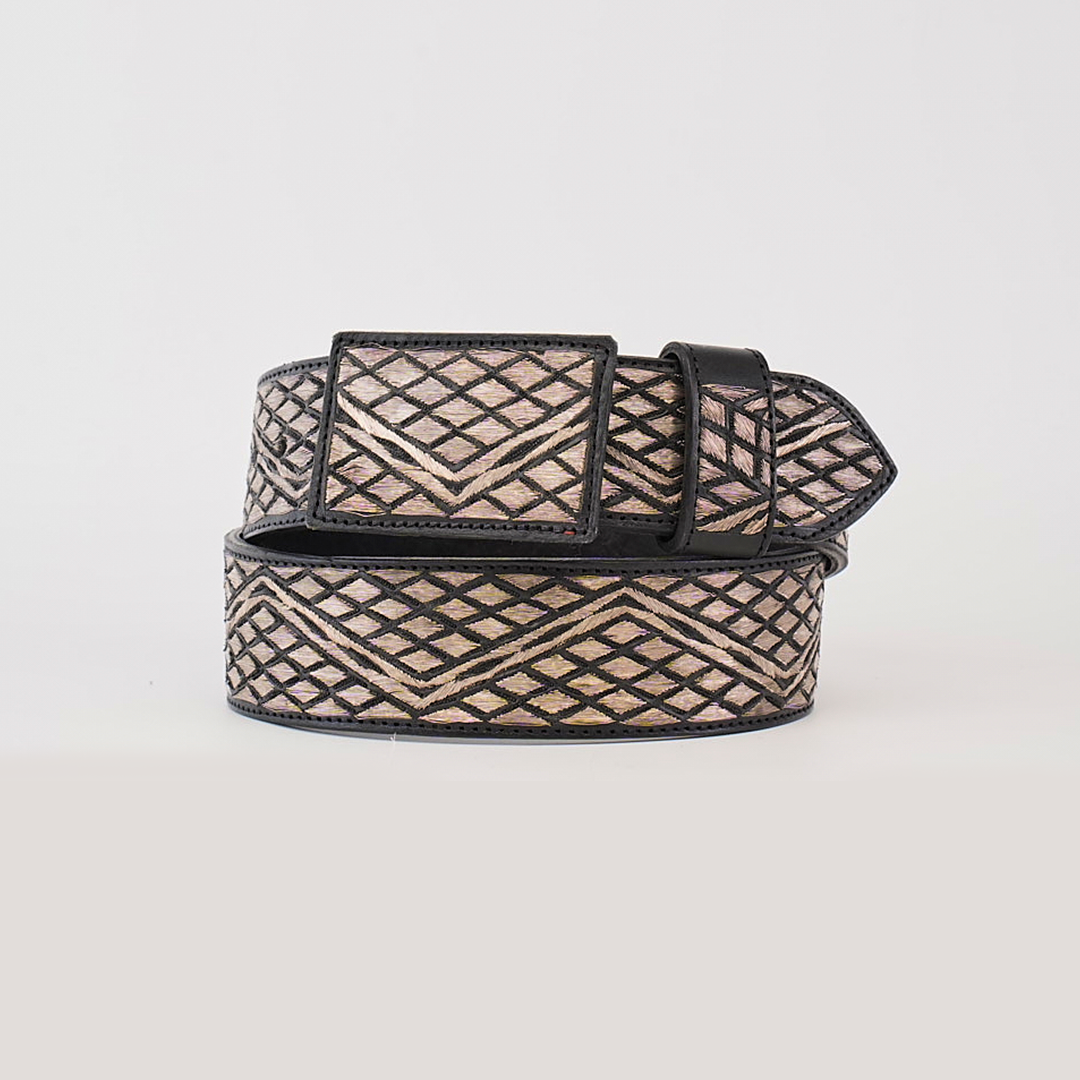 The Artisanal Handmade Silver Belt Rombos showcases a geometric pattern of intersecting diagonal metallic lines with silver thread embroidery. It features a rectangular buckle, black edge, and its design is contrasted beautifully against a plain white background.