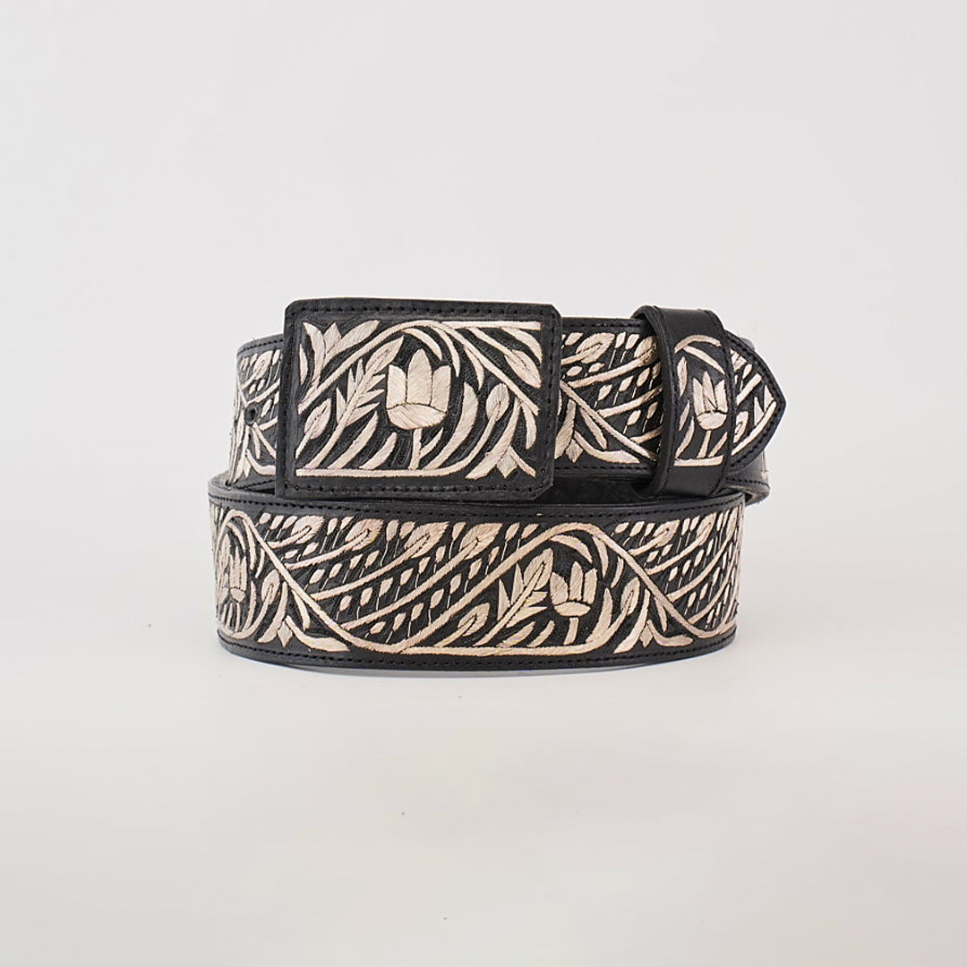 The Artisanal Handmade Silver Belt Flowers Deluxe is a luxurious black belt, intricately designed with silver thread embroidery featuring floral and leafy patterns. Handcrafted and showcased rolled up on a plain white background, it highlights its decorative beauty along the length.