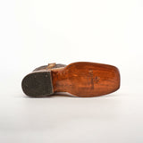 The bottom view of an Exotic Caiman Hornback boot displays a wooden sole and black rubber heel with TEK SQUARED logo. This antique rodeo toe cowboy boot, made from genuine tan caiman leather, is shown on its side against a plain white background.