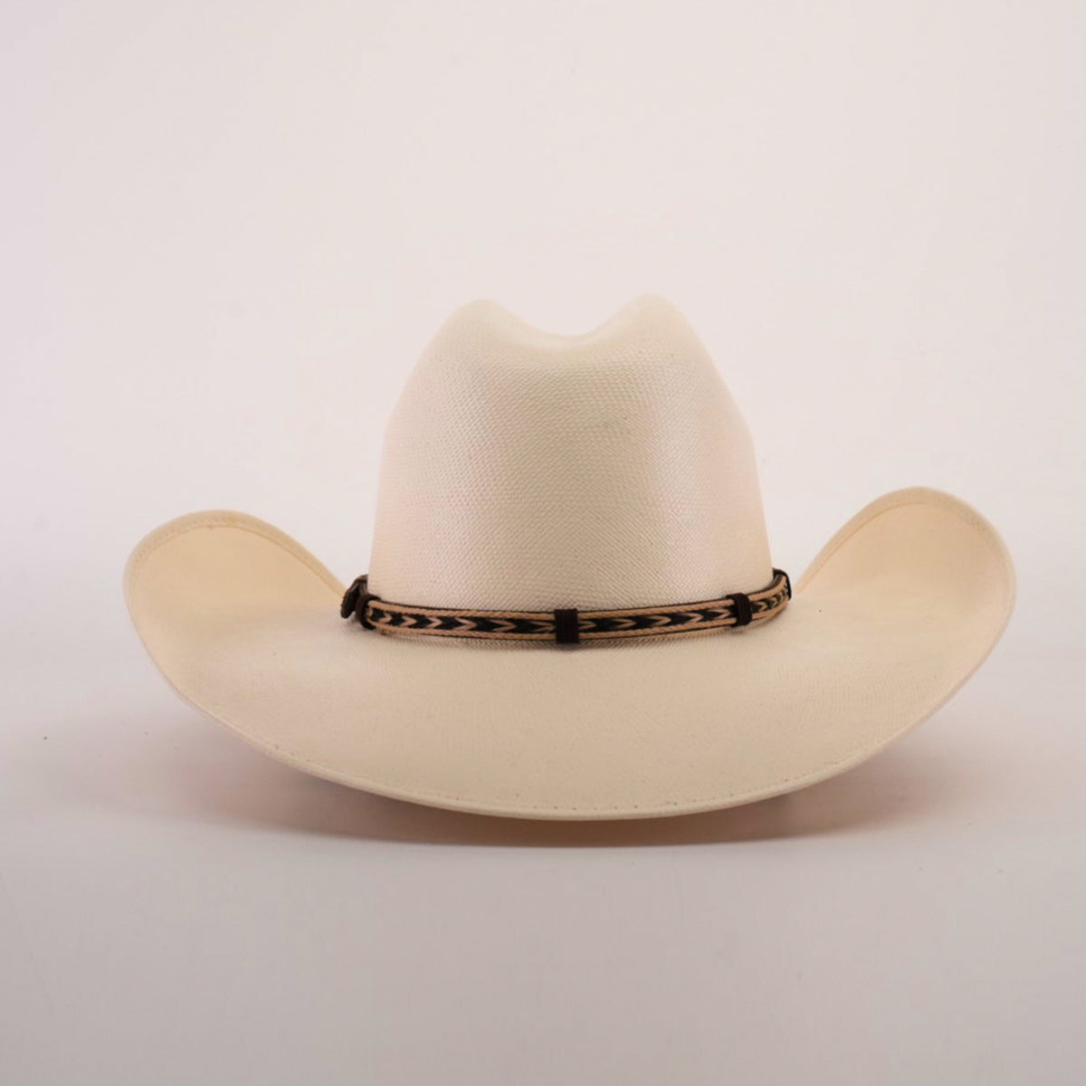 Set against a plain backdrop, the 5000x Chihuahua Straw Hat displays its fine craftsmanship with a light-colored wide brim and a decorative brown band encircling the crown.