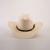 The 1000X Sinaloa Straw Hat features an elegant design with a wide brim, a black band adorned with silver conchos, and a plain white background.