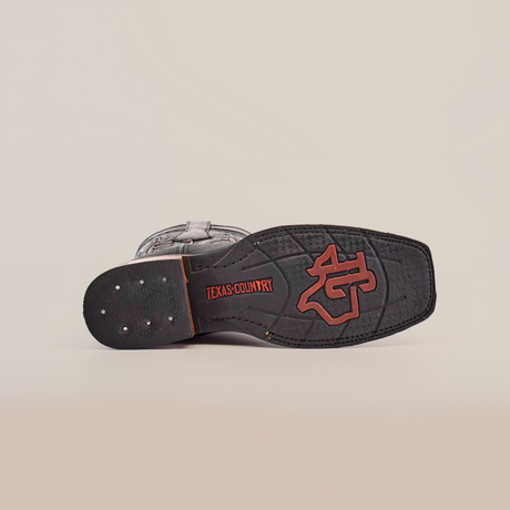 The Cheyenne Black boot has a rectangular sole crafted from premium cowhide leather, featuring TEXAS COUNTRY in red and a boot spur logo. The slip-resistant sole includes metal studs and stitching for added durability.