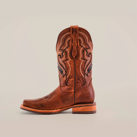 The Fresno Shedron - Slip Resistant Sole - Rodeo Toe cowboy boot in brown, crafted from cowhide leather, features intricate shaft patterns, a slightly pointed toe, and a stacked heel. It is set against a plain white background, showcasing its stylish design and substance.