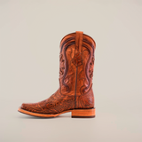 The Handtooled Leave Cogñac cowboy boot displays intricate floral and swirl engravings on premium brown cowhide leather. It features a low heel, rodeo toe, slip-resistant sole, and a side pull-strap, all showcased against a plain white background.