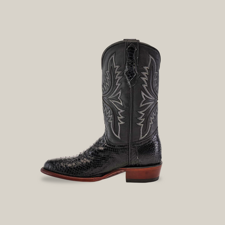 The Exotic Python - Black - Round Toe cowboy boot features a pointed toe and is crafted from python leather with a textured snakeskin pattern. It boasts intricate white western stitching and is complemented by a contrasting brown sole.