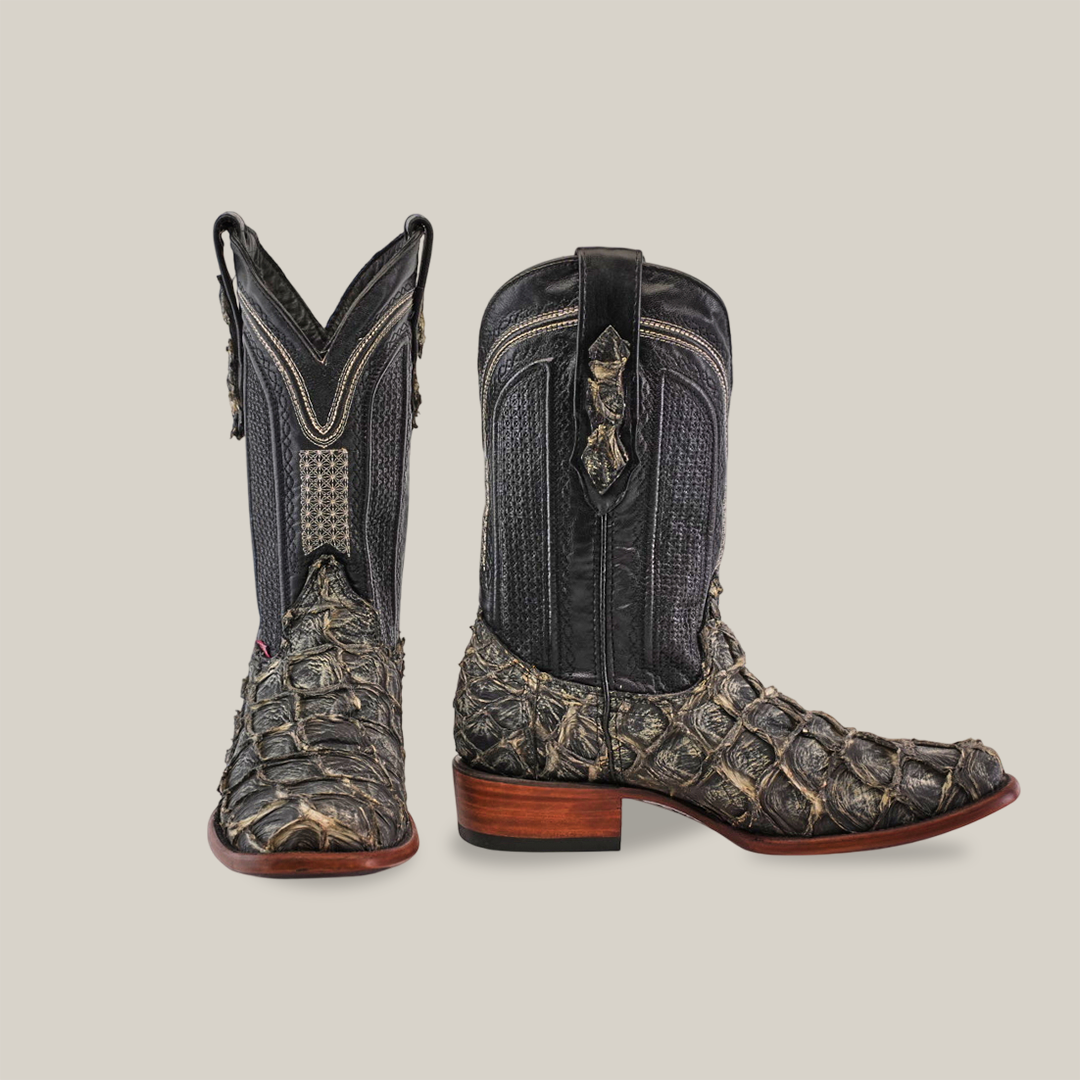 A pair of dark, textured cowboy boots made from genuine Piraruco fish leather, featuring a scaly pattern and rich details with a wooden heel. The left boot is toe-forward and the right shows a side view, showcasing the unique design of the Exotic Piraruco Fish - Rustic Bone - Narrow Square Toe as exotic Western footwear.