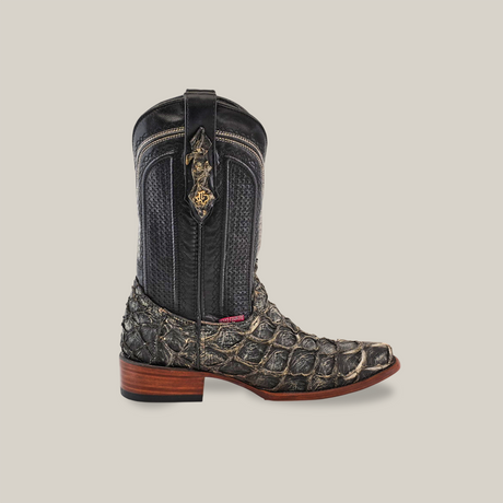 The Exotic Piraruco Fish - Rustic Bone boot features a textured, reptile-like pattern on the lower part from genuine fish leather, with smooth leather on the shaft. It has a wooden heel, intricate decorative stitching, and an emblem near the top against a solid beige backdrop.