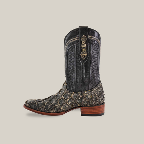 The single Exotic Piraruco Fish boot showcases genuine fish leather with a rugged design in dark and light brown. It features detailed stitching, a decorative strap with buckle, and a wooden heel against a plain background. The style is dubbed Rustic Bone - Narrow Square Toe.