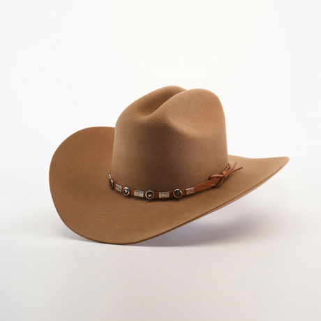 The 6X Sinaloa Fawn, a brown cowboy hat with a wide brim and decorated band with round metal accents and a side knot, embodies rich Western heritage. Crafted from premium sheeps wool, it is showcased on a plain white background.