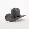 The 6X Leandro Oxford, a dark gray cowboy hat made from premium sheeps wool, boasts a wide brim and a decorative band with metallic accents, set against a plain white background.