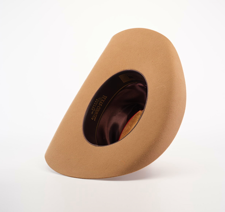 The 6X Leandro Fawn, a tan felt hat made from premium sheeps wool, is displayed on its side to showcase its dark brown interior against a plain white background.