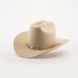 The 6X 2 Carnales Bone is a tan felt cowboy hat made from sheep wool, showcasing a wide brim and a decorative band with metal accents. Small rectangular pieces and a leather string add charm to the band, while the classic western hat rests elegantly on a white background.