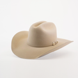 The 100X Tony Lama Belly is a beige cowboy hat crafted from premium beaver fur, exuding Western elegance with a wide brim and metal-accented decorative band, beautifully set against a plain white background to embody true Western spirit.