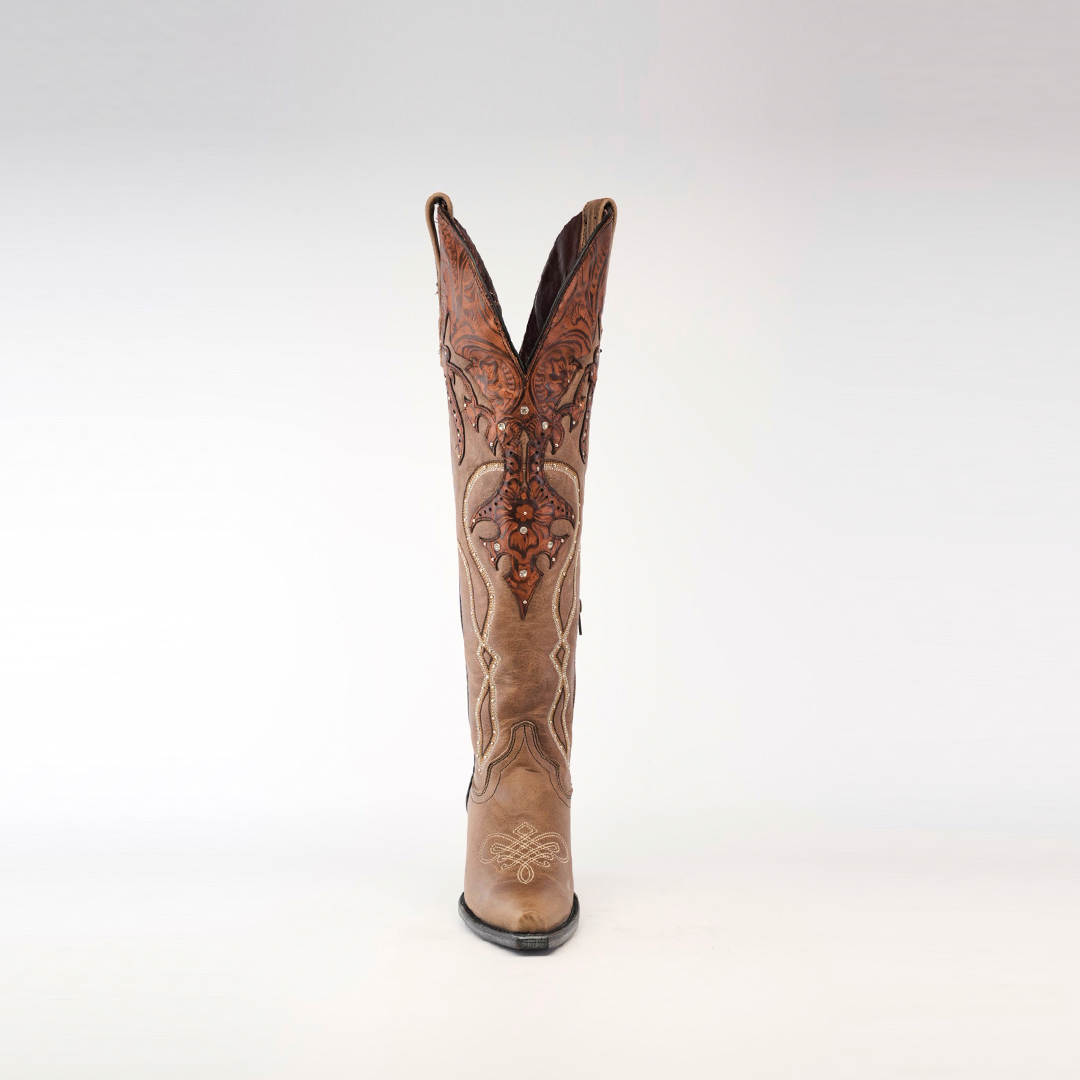 A tall cowboy boot stands against a white background, featuring intricate brown embroidery and decorative stitching. This handcrafted design evokes the charm of artisanal footwear typical of Miriam Cappuccino - Tall Shaft - Snip Toe boots.