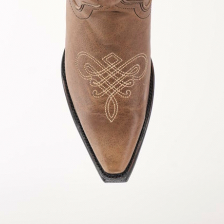 The Miriam Cappuccino boot features a snip toe with intricate white stitching that exemplifies artisanal craftsmanship on brown leather. Its black sole complements the detailed design, all beautifully showcased against a plain white backdrop.