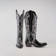 A pair of Artemisa Patent Black boots with a tall shaft, snip toe, and intricate silver embroidery. These shiny, premium leather cowboy boots with a low heel are elegantly displayed against a plain white background.