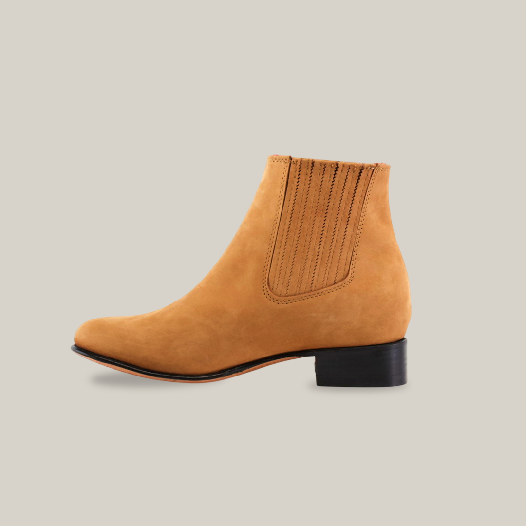 The Prime Suede Honey Round Toe is a tan leather ankle boot with Western styling, a low black heel, elastic side panels, and decorative stitching, showcased against a plain white background.