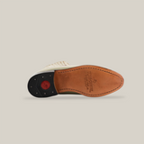 The image displays the bottom of a handcrafted Napa Bone - Round Toe boot from the western wear collection, with a brown leather sole, black heel, text markings, red logo, and edge stitching on a plain white background.
